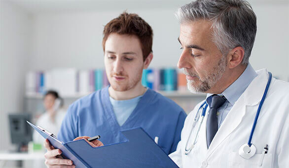 medical assistant looking at a file with a doctor